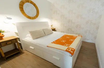 a small bedroom with a white bed and a mirror at Urban Vistahermosa in El Puerto de Santa María