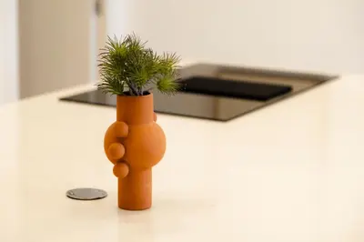 an orange vase with a plant in it on a counter at Urban Vistahermosa in El Puerto de Santa María