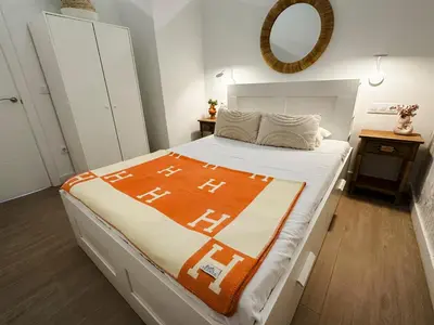 a bedroom with a bed with an orange blanket on it at Urban Vistahermosa in El Puerto de Santa María
