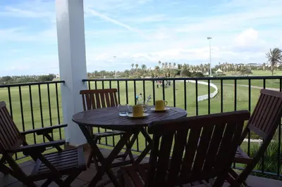 a table and chairs on a balcony with a view of a field at Apartamento Costa Ballena Playa y Golf in Cádiz