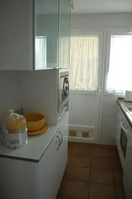 a kitchen with white cabinets and a microwave at Apartamento Costa Ballena Playa y Golf in Cádiz