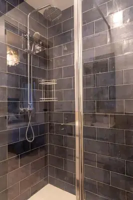 a bathroom with a shower with black tiles at Arenas de la Victoria by Gades Gestión in Cádiz