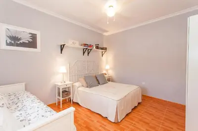 a white bedroom with a bed and a table at Apartamento Centro Jerez Carbón in Jerez de la Frontera