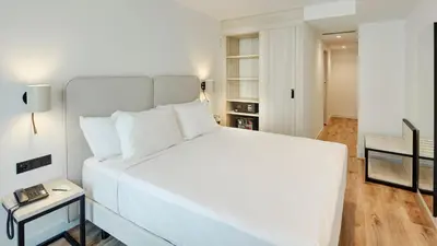 a large white bed in a room with a table at Sercotel Cruz Del Mar in Chipiona