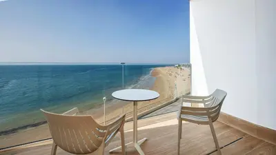 a table and two chairs on a balcony with the ocean at Sercotel Cruz Del Mar in Chipiona