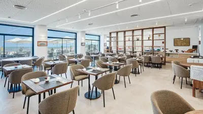 a restaurant with tables and chairs and windows at Sercotel Cruz Del Mar in Chipiona