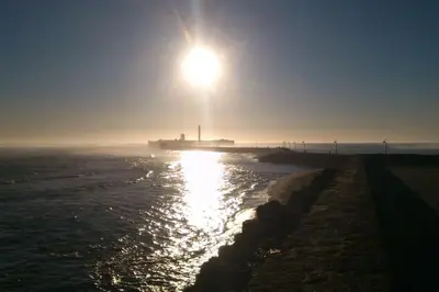 a sun shining over the water with a pier at A 5 min de la playa Victoria y del Htal Pta Mar in Cádiz