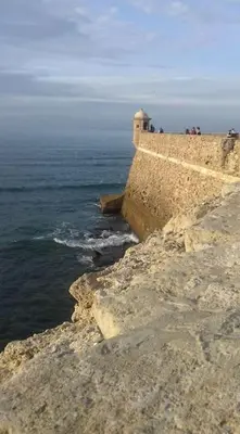 a group of people standing on a cliff near the ocean at A 5 min de la playa Victoria y del Htal Pta Mar in Cádiz