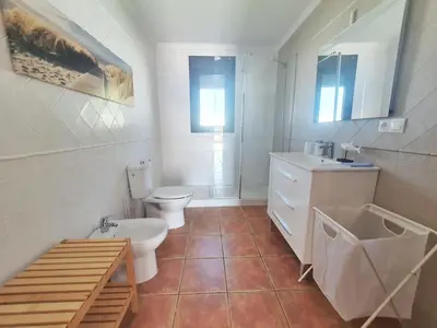 a white bathroom with a toilet and a sink at La Casita de Nora in Conil de la Frontera