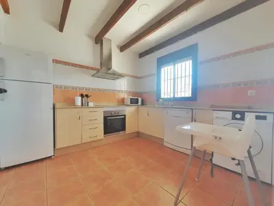 a kitchen with a white refrigerator and a table at La Casita de Nora in Conil de la Frontera