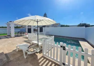 a patio with an umbrella and chairs and a pool at La Casita de Nora in Conil de la Frontera