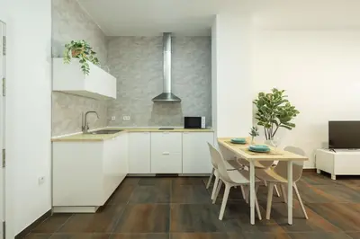 a kitchen with white cabinets and a table and chairs at Antiguo Balneario in Cádiz