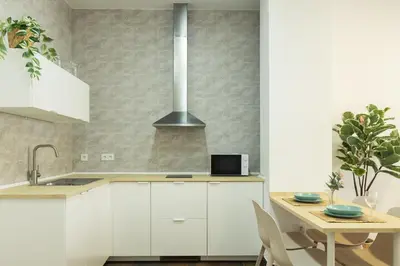 a kitchen with white cabinets and a wooden table at Antiguo Balneario in Cádiz