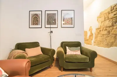 two green chairs in a room with paintings on the wall at El Rincón de Pepa y Juan in Jerez de la Frontera
