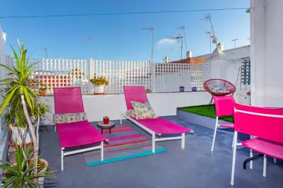 a group of pink chairs and a table on a balcony at Wehostcostaluz EL NIDO GADITANO in Cádiz