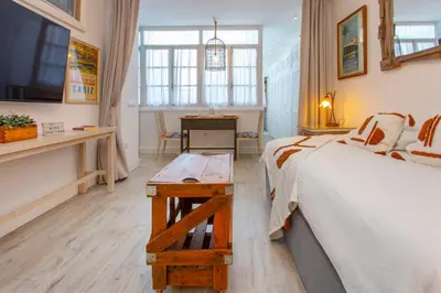 a bedroom with two beds and a television and a table at Wehostcostaluz EL NIDO GADITANO in Cádiz