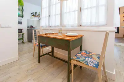 a table and a chair in a room with a kitchen at Wehostcostaluz EL NIDO GADITANO in Cádiz