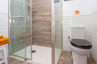 a bathroom with a toilet and a glass shower at Wehostcostaluz EL NIDO GADITANO in Cádiz