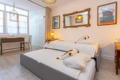 two beds in a room with a table and a desk at Wehostcostaluz EL NIDO GADITANO in Cádiz