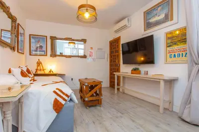 a bedroom with a bed and a desk and a television at Wehostcostaluz EL NIDO GADITANO in Cádiz