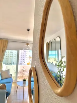 a mirror in a living room with a blue couch at Vistas al mar primera linea playa Valdelagrana in El Puerto de Santa María