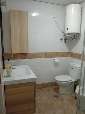 a bathroom with a white toilet and a sink at Apartamento Buhaira Free Parking in Cádiz