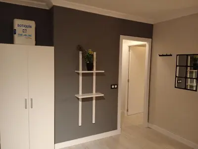 a room with a gray wall with a white shelf at Apartamento Buhaira Free Parking in Cádiz