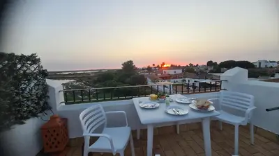 a white table and chairs on a balcony with the sunset at Casa Salina in Chiclana de la Frontera