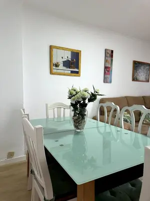 a dining room table with a vase of flowers on it at Paraíso Frente al Mar en Cádiz in Cádiz