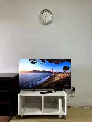 a flat screen tv on a wall with a clock at Paraíso Frente al Mar en Cádiz in Cádiz