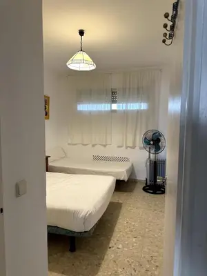 a bedroom with two beds and a window with a fan at Paraíso Frente al Mar en Cádiz in Cádiz