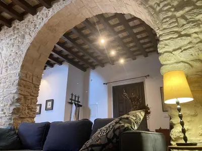 a living room with a couch and a stone wall at Arcos de la Loba by casitasconencantoes in Medina Sidonia