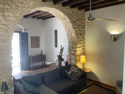 a living room with a blue couch and a stone wall at Arcos de la Loba by casitasconencantoes in Medina Sidonia
