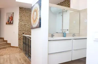 a bathroom with white cabinets and a brick wall at Apartamento Dúplex Bahia Sur in San Fernando