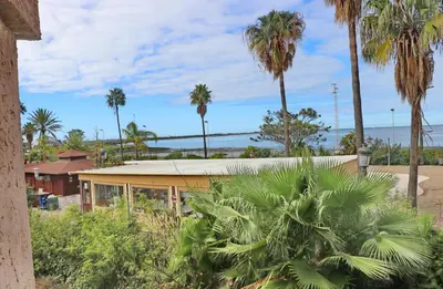 a house with palm trees and the ocean in the background at Apartamento Dúplex Bahia Sur in San Fernando