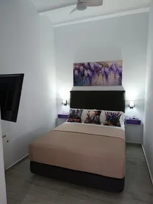 a bedroom with a bed with a painting on the wall at Casa Sahar in Arcos de la Frontera