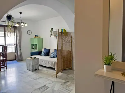 a living room with a bed and a table at Apartamento Las Palmeras - Ole Solutions in Jerez de la Frontera