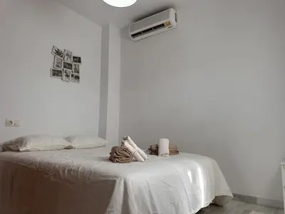 a white bedroom with a bed with a heater on it at Apartamento Las Palmeras - Ole Solutions in Jerez de la Frontera