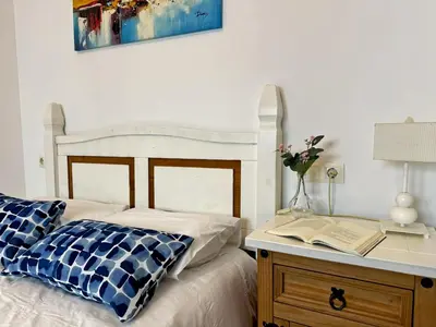 a bedroom with a bed and a table with a book at Apartamento Las Palmeras - Ole Solutions in Jerez de la Frontera
