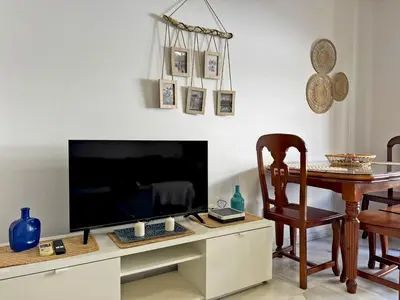 a living room with a television and a table with a chair at Apartamento Las Palmeras - Ole Solutions in Jerez de la Frontera