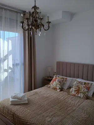 a bedroom with a bed with a chandelier and a window at Balcon mirador de las Salinas in Sanlúcar de Barrameda