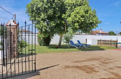 a gate with two blue chairs next to a tree at Casa Ana in Conil de la Frontera