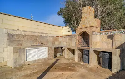 an outdoor kitchen with a stone wall and a building at Amazing Home In La Barca De La Florida in La Barca de la Florida