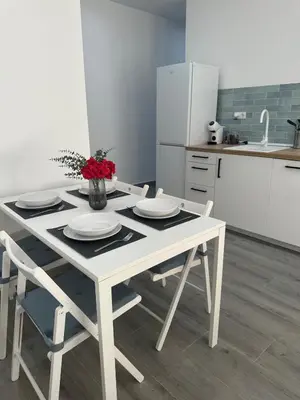 a kitchen with a table with plates and flowers on it at Apartamentos playa in Sanlúcar de Barrameda