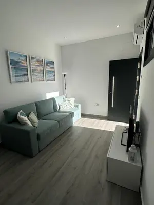 a living room with a blue couch and a table at Apartamentos playa in Sanlúcar de Barrameda