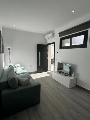 a living room with a green couch and a television at Apartamentos playa in Sanlúcar de Barrameda