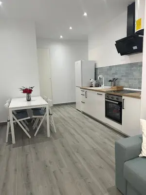 a kitchen with a table and a stove and refrigerator at Apartamentos playa in Sanlúcar de Barrameda