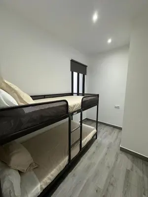 a bedroom with two bunk beds and a wooden floor at Apartamentos playa in Sanlúcar de Barrameda