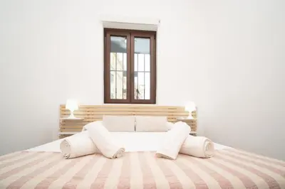a white bedroom with a bed with a window at SibsSanlucar Carril San Diego 2 Coqueto Centrico Terraza in Sanlúcar de Barrameda