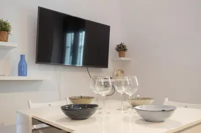 a table with wine glasses and a television on a wall at SibsSanlucar Carril San Diego 2 Coqueto Centrico Terraza in Sanlúcar de Barrameda